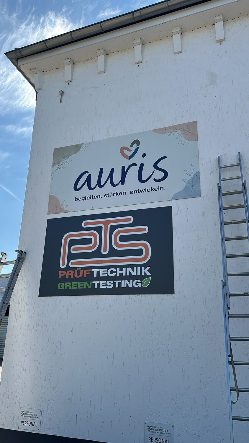 Zwei Fassadenschilder: auris und PTS Prüftechnik